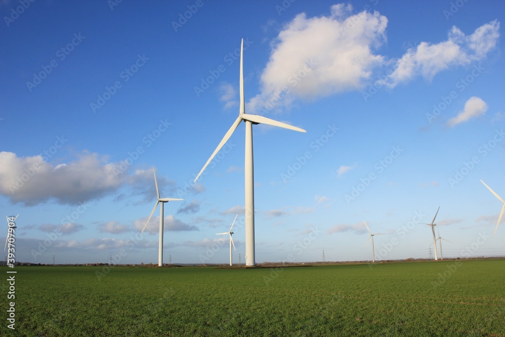 Wind farm turbines that produce electricity energy. Windmill Wind power technology productions Wind turbines standing in green field - stock footage Wind farm turbines that produce electricity energy. Windmill Wind power technology productions Wind turbines standing in green field - stock footage