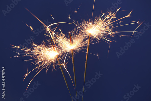Bright burning sparkler on blue background  closeup