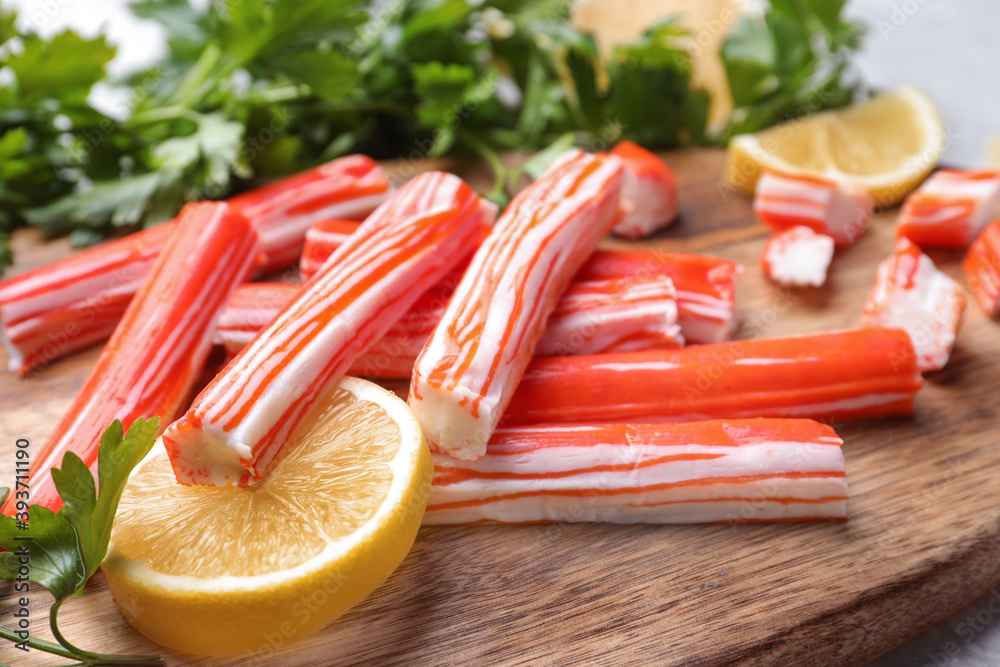 Delicious crab sticks with lemon and parsley on wooden board, closeup Delicious crab sticks with lemon and parsley on wooden board, closeup