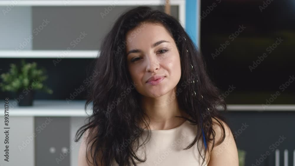 Smiling young woman brunette looking at camera at home office. Happy millennial female with pretty face posing indoors in apartment. Smiling young woman brunette looking at camera at home office. Happy millennial female with pretty face posing indoors in apartment.