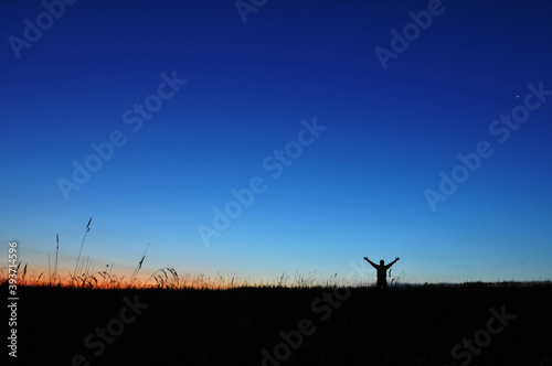Sunrise and silhouette of a man standing in a field