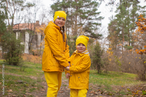 Cute little boy and a girl - brother and sister - in identical yellow costumes and hats walking in the forest. Cosiness, family