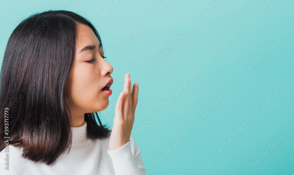 Portrait female bored yawning tired covering mouth with hand, Young beautiful Asian woman sleepy covering opened mouth with palm, studio shot isolated on a blue background Portrait female bored yawning tired covering mouth with hand, Young beautiful Asian woman sleepy covering opened mouth with palm, studio shot isolated on a blue background
