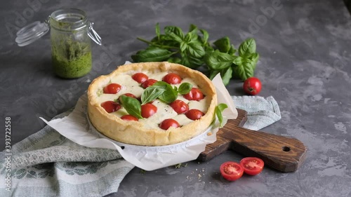 Pie with cheese and tomatoes. Basil falls on the cake. Slow motion.