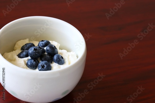Obraz na płótnie A close up shot of natural Greek style yogurt with some fresh blueberries on top in a white ceramic bowl. w salonie