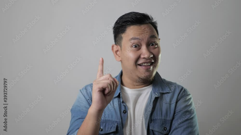 Young Asian man looked happy thinking and looking up, having good idea. Half body portrait against gray wall Young Asian man looked happy thinking and looking up, having good idea. Half body portrait against gray wall