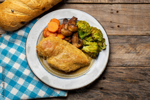 Chicken in mustard sauce with roasted vegetables in wooden background