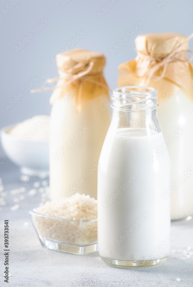 Rice milk in bottles, closeup, gray background. Non dairy alternative milk. Healthy vegetarian food and drink Rice milk in bottles, closeup, gray background. Non dairy alternative milk. Healthy vegetarian food and drink