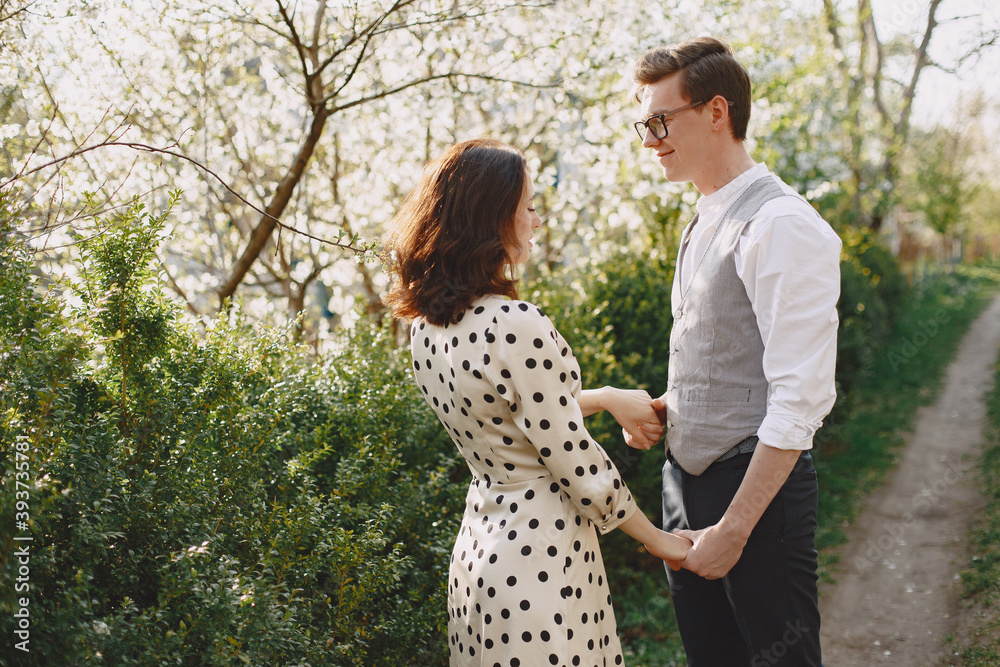 Man and woman in blooming garden on spring day. Couple in love spend time in spring garden. Flowers on background. Man and woman in blooming garden on spring day. Couple in love spend time in spring garden. Flowers on background.