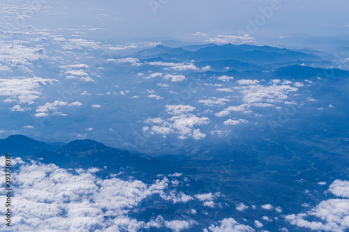 White clouds and ridges of mountains outside the plane window 