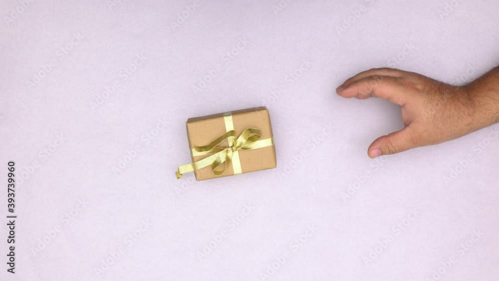 Woman hand giving Christmas gift with gold ribbon to man. Stop motion Woman hand giving Christmas gift with gold ribbon to man. Stop motion