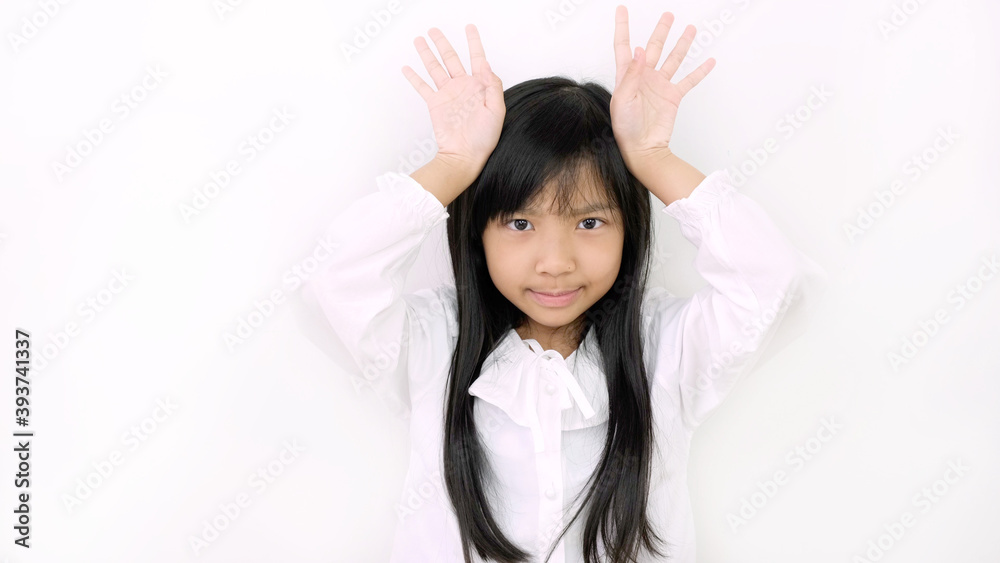 Asian child girl is smiling cute and uses her finger to act like a deer on a white background. Asian child girl is smiling cute and uses her finger to act like a deer on a white background.