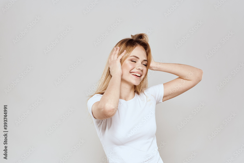 cheerful blonde in a white t-shirt gesturing with her hands light background cheerful blonde in a white t-shirt gesturing with her hands light background
