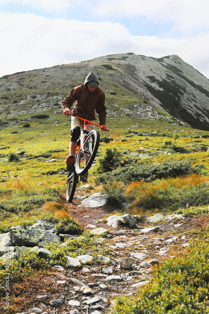 Young male cyclist going down a bike from a high mountain. A man going down the mountain on a mountain bike.