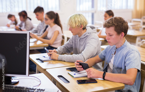 Portrait of teen pupils using mobile phones during lesson