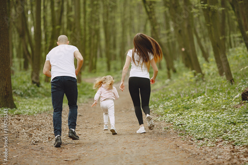 Family in a summer forest. Woman and man in a white t-shirts. Daughter with parents. © hetmanstock2