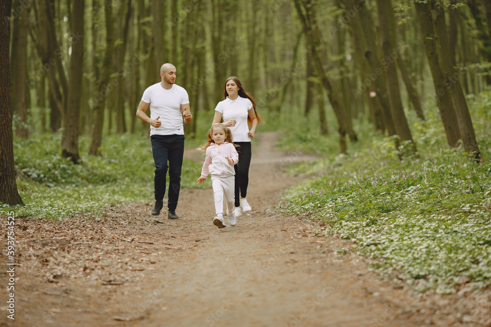 Fototapeta premium Family in a summer forest. Woman and man in a white t-shirts. Daughter with parents.