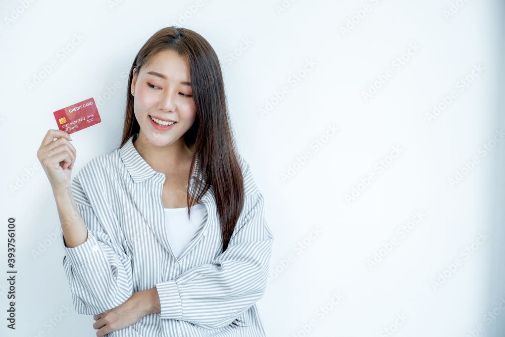 Portrait of a lovely young Asian beautiful woman with long hair holding a red credit card, her eyes sparklingly at the camera. Ready to pay shopping according to discounted products Portrait of a lovely young Asian beautiful woman with long hair holding a red credit card, her eyes sparklingly at the camera. Ready to pay shopping according to discounted products