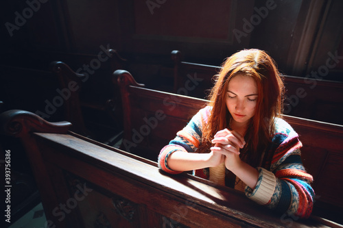 Young Caucasian woman prays in a church. 