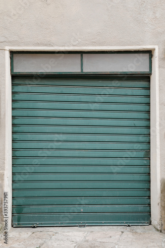 Weathered and damaged gerrn garage door, shutter rolled up and bland, space for text and perfect background, vertical format