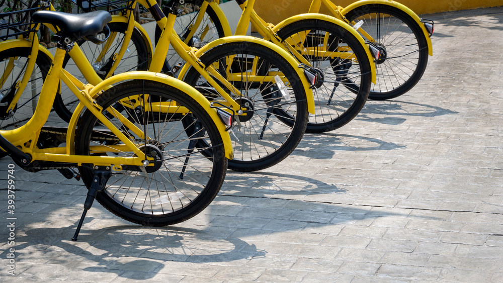 Row of yellow bikes parked on cobblestone pavement in public area