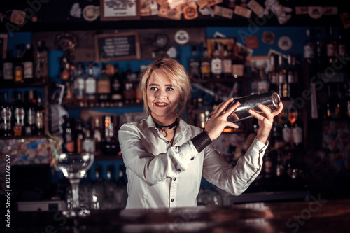 Charismatic woman bartender demonstrates his professional skills while standing near the bar counter in bar