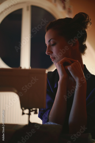 Woman tailor working on a sewing machine at home.