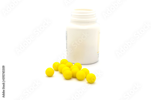 Round yellow pills and plastic jar isolated items on white background.