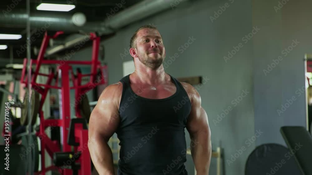 An attractive man bodybuilder performing Side raise exercise with dumbbells at gym An attractive man bodybuilder performing Side raise exercise with dumbbells at gym