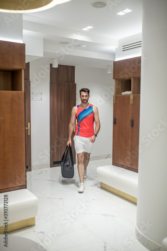 Sporty young man in bright tshirt entering the changing room