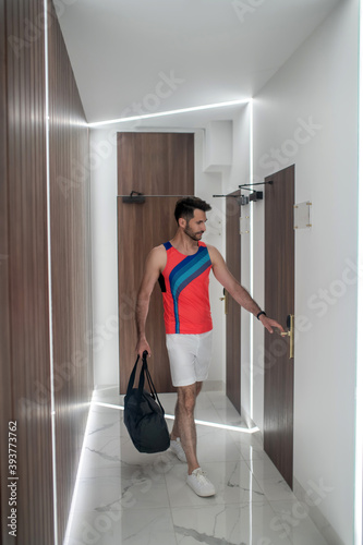 Sporty man in bright tshirt walking in the corridor