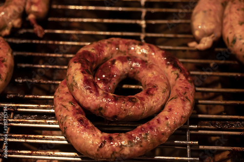 Coil of juicy beef sausage grilling over a BBQ photo