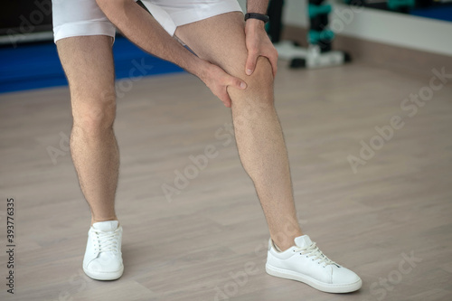 Close-up of male hands massaging painful knee in the gym