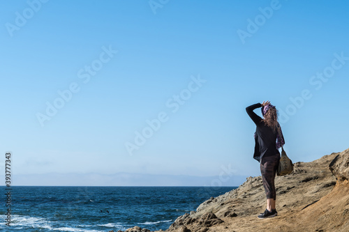 Woman standing on cliff looking onto the pacific ocean in Bodega Bay Northern California