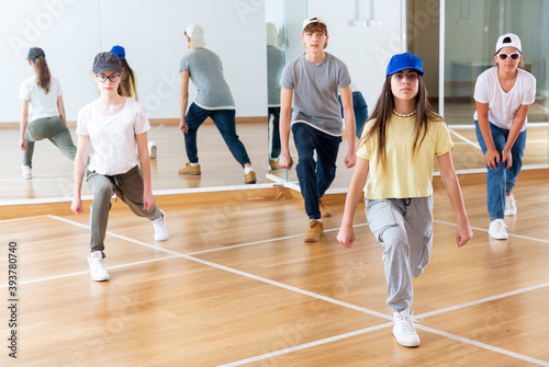 Focused teenage hip hop dancers doing dance workout during group class