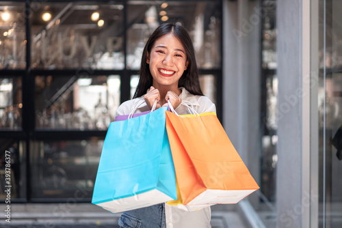 Portrait of Asian girl excited beautiful girl happy smiling with holding shopping bags relaxed expression, Positive emotions shopping, lifestyle concept