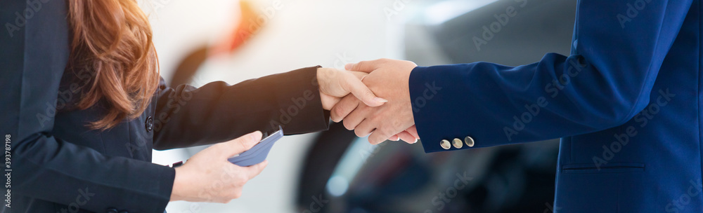 Auto business banner background, close up of dealer shaking hands in auto show or salon, concept dealer cars for sale.