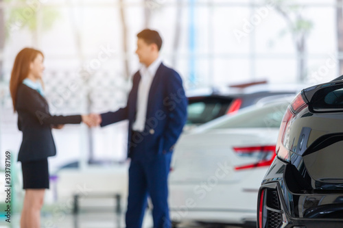 Selective focus on a new car and blur the dealership professional salesman and his client shaking hands. concept dealer Cars For Sale. © tong2530