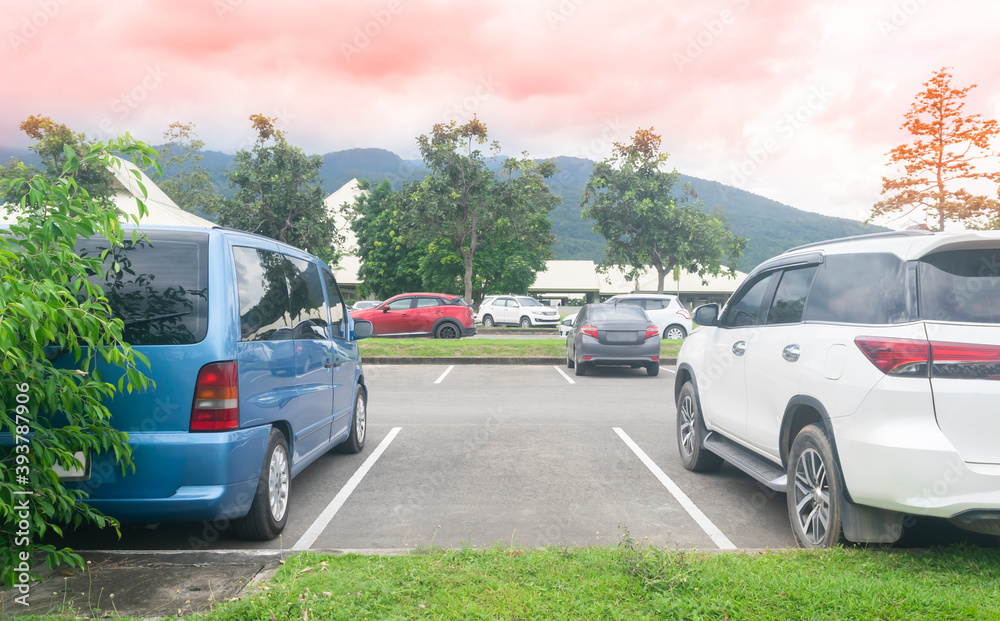 Car parked in asphalt parking lot and empty space parking with trees, mountain, beautiful sky background. Outdoor parking lot with fresh nature, green environment transportation and technology