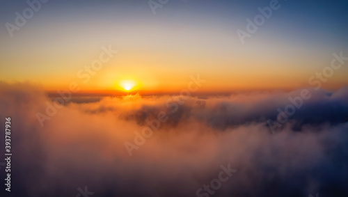Aerial point of view of a golden sunset above the clouds