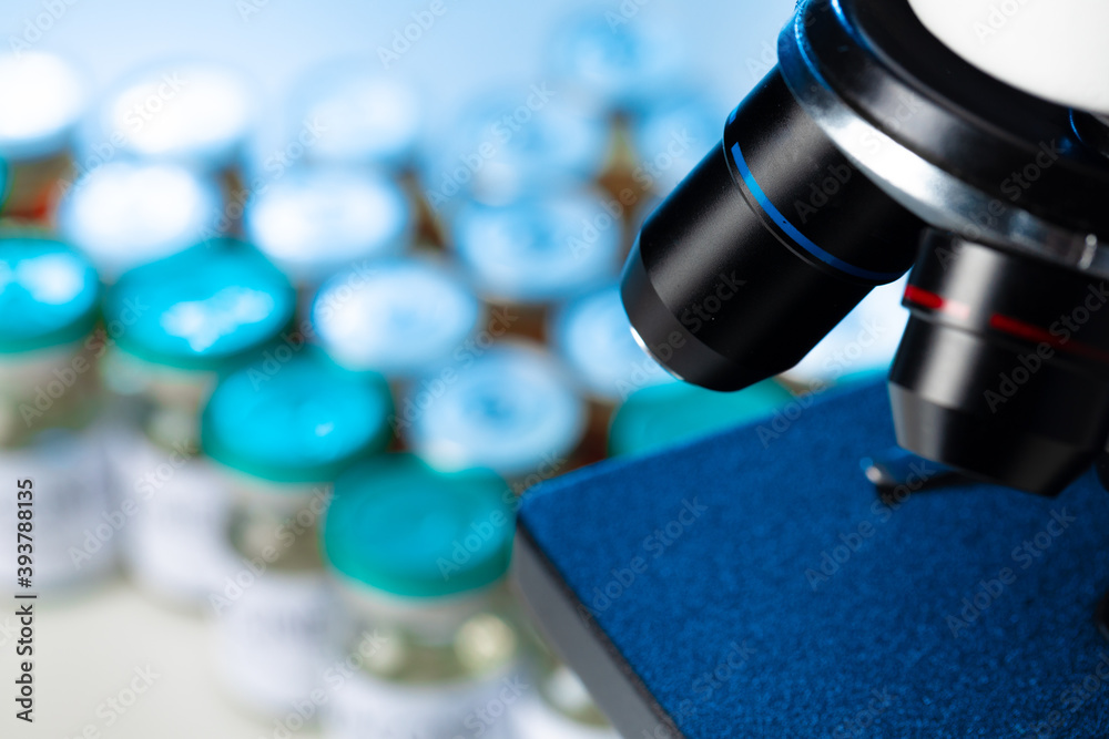 Medical vial with medication near microscope close up Medical vial with medication near microscope close up