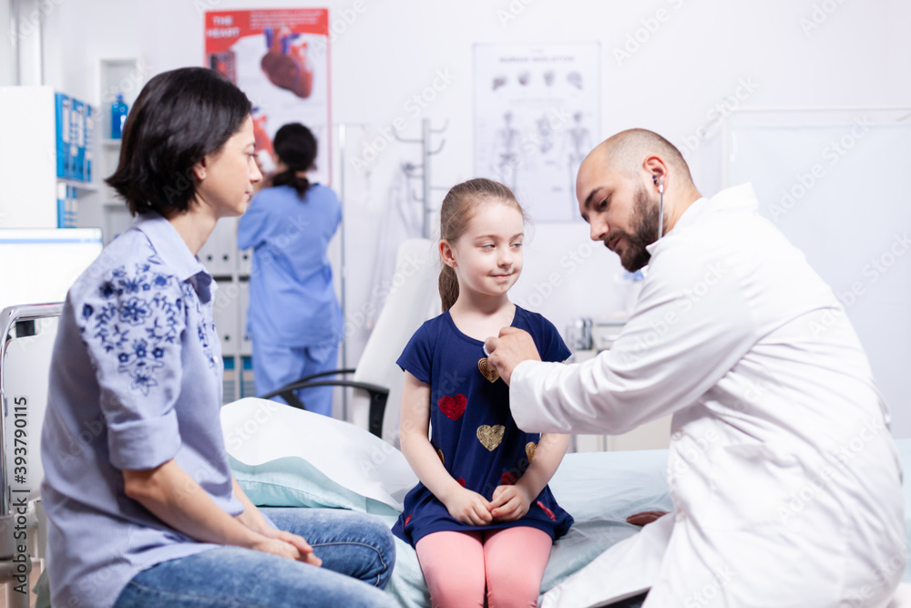 Obraz premium Doctor listening lungs of sick girl using stethoscope in hospital room during consultation. Healthcare physician specialist in medicine providing health care services treatment examination.