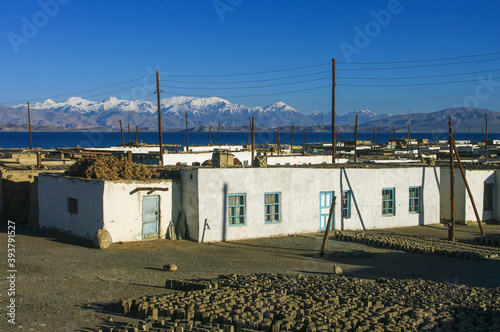 Foto Karakul village after sunrise, with lake Karakul and snow-capped mountains in th