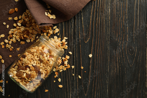 Glass jar with tasty granola on wooden background