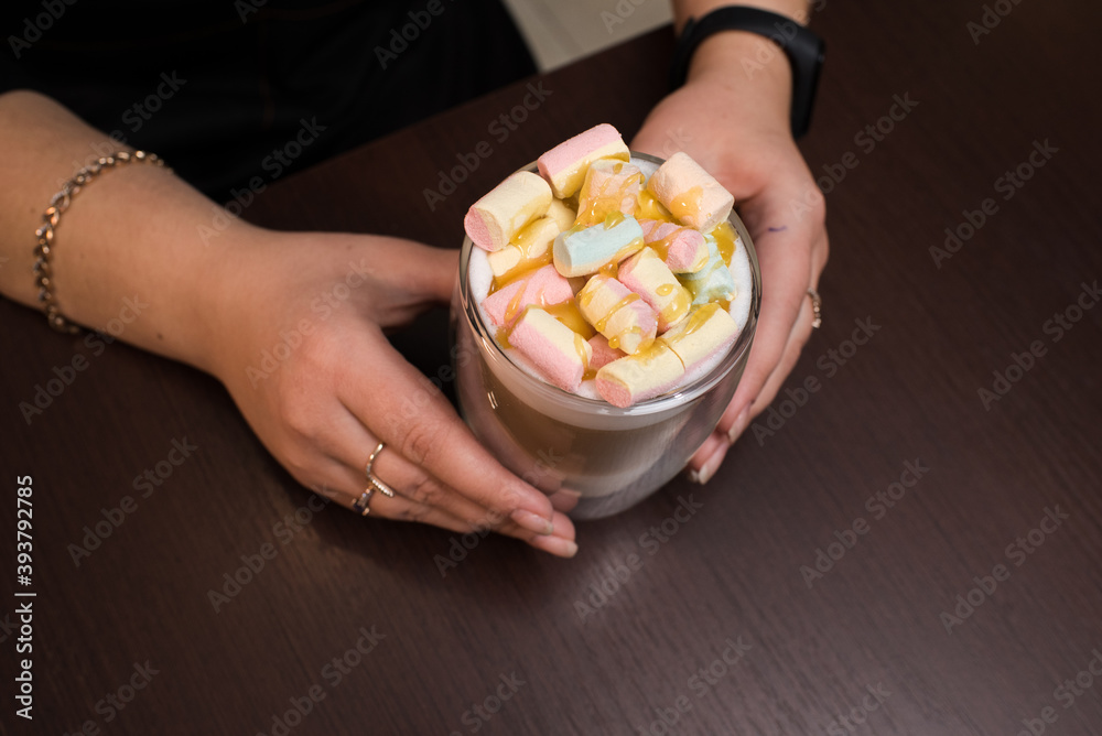Close-up female hands holding coffee latte with marshmallows Close-up female hands holding coffee latte with marshmallows