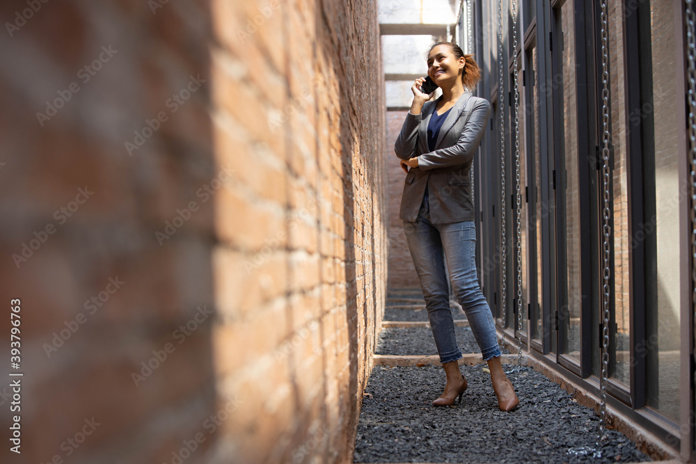 young businesswoman talking on the phone beside a modern wall