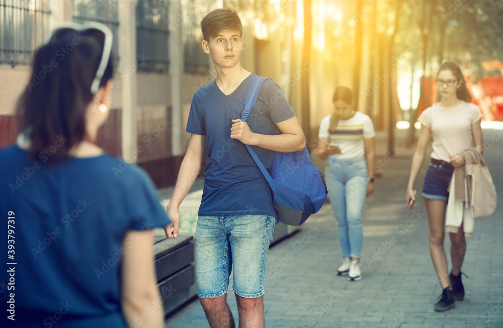 Positive teenager walking in the street, carrying a bag on one shoulder
