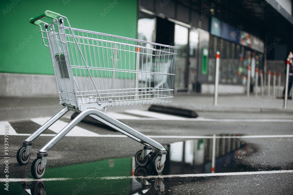 a supermarket basket is on the asvalt and a puddle of water, a wheelchair a supermarket basket is on the asvalt and a puddle of water, a wheelchair