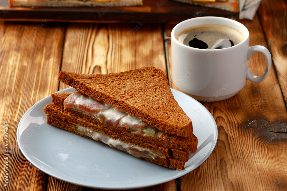 Toast sandwich and cup of coffee on napkin on wooden table