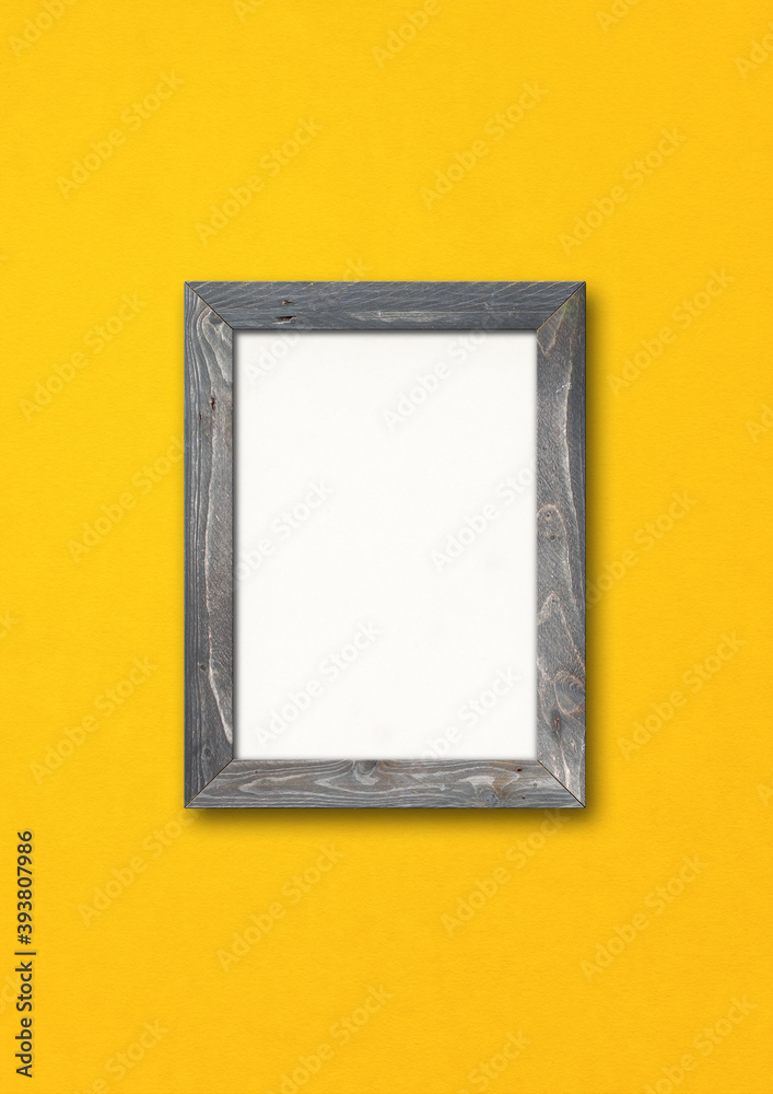Old rustic wooden picture frame hanging on a yellow wall Old rustic wooden picture frame hanging on a yellow wall